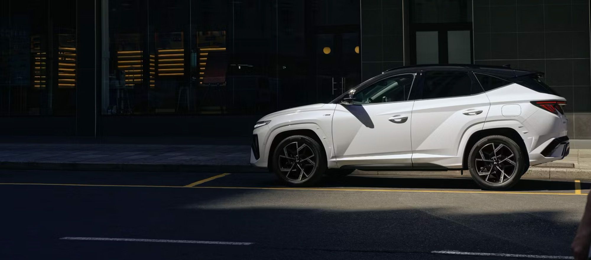Seitenprofil eines Hyundai TUCSON, welcher leicht im Schatten versteckt ist