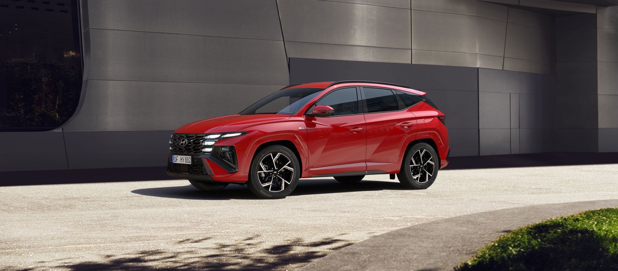 Ein Seitenprofil eines Hyundai TUCSON vor einem modernen Gebäude